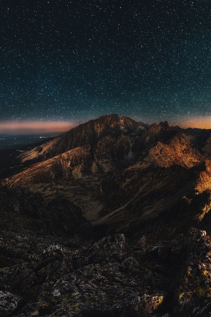 A starry night sky over a wide mountain range at dusk